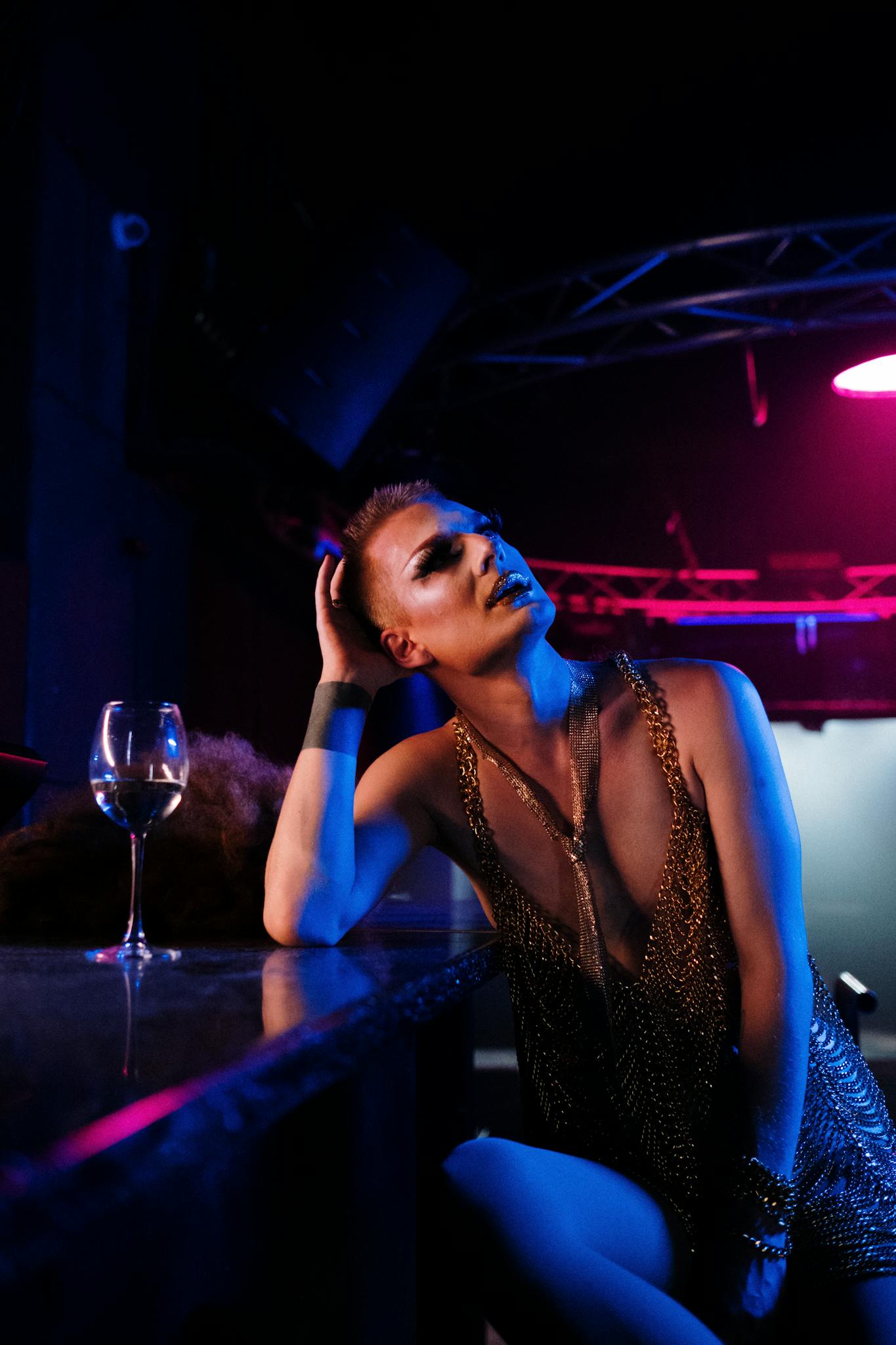 Captivating image of a glamorous drag performer posing at a nightclub bar under dramatic lighting.