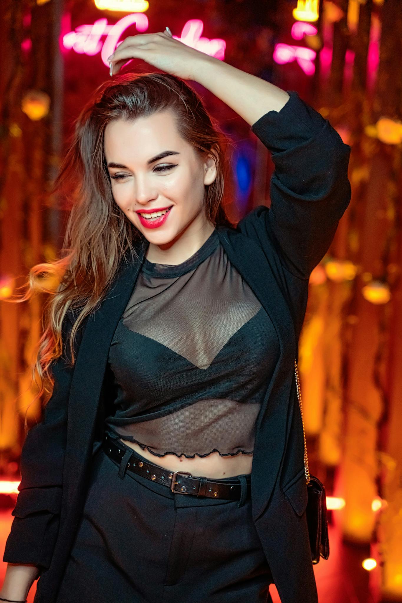 Stylish woman in sheer fabric top enjoying vibrant nightlife in Dubai.